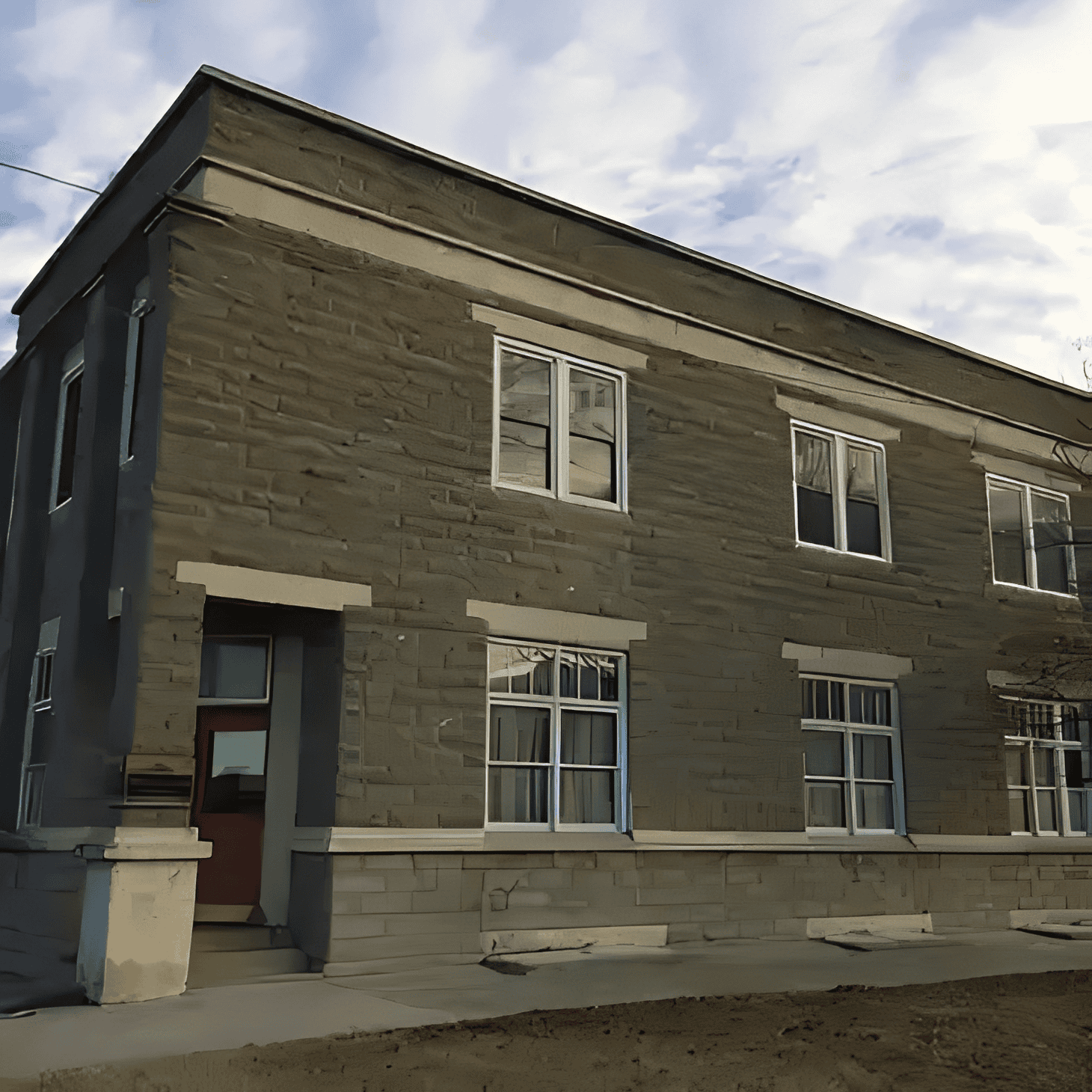 Two-story stone building under cloudy sky