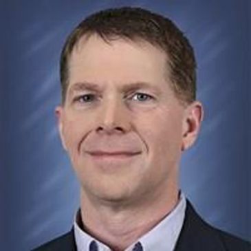 Professional headshot with blue backdrop