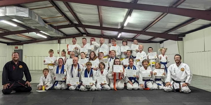 Martial arts students holding achievement certificates